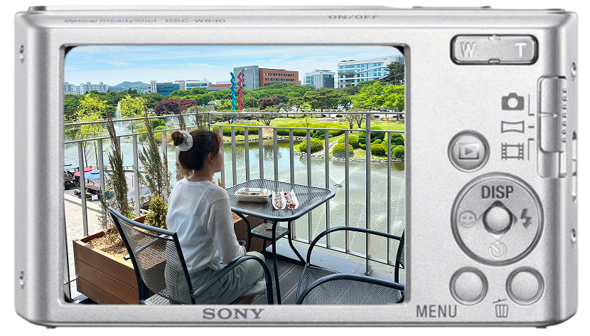 Heeji sitting at a table overlooking the KAIST duck pond, framed inside a Sony digital camera